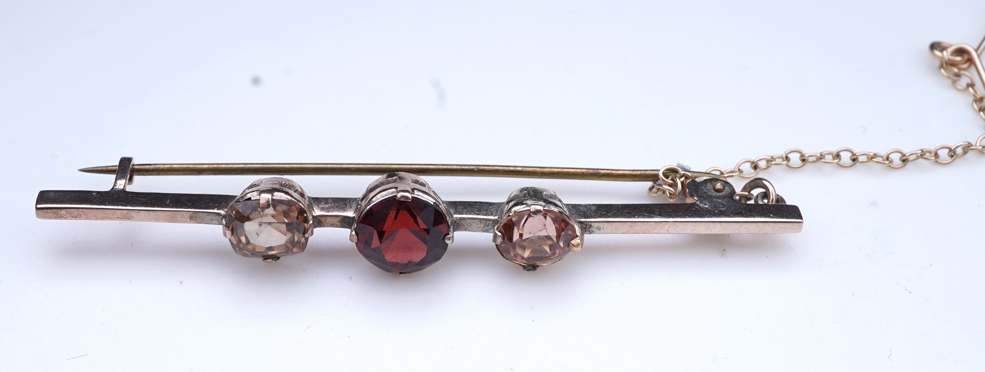 A Victorian yellow metal, amethyst and garnet cluster set brooch, 22mm, an early 20th century yellow metal and seed pearl set heart shaped locket, a yellow metal, garnet and zircon set three stone bar brooch and a tortoi